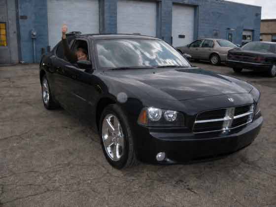 Proud customers waving from a freshly repaired Dodge Charger