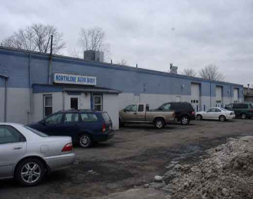Northline Auto Body with finished cars and a dirty late-winter snow pile