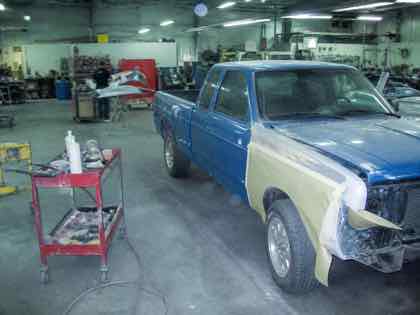 A blue pickup undergoing paint preparation
